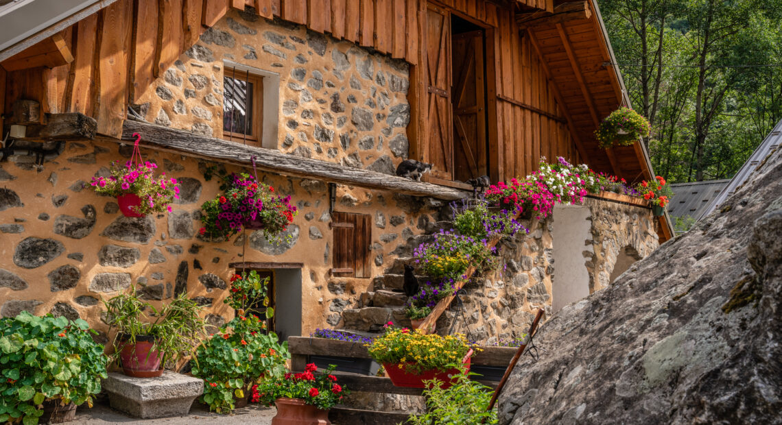 Maison de village de montagne en pierre, fleurie et colorée, typique des villages d'alpinisme des Écrins dans les Hautes-Alpes